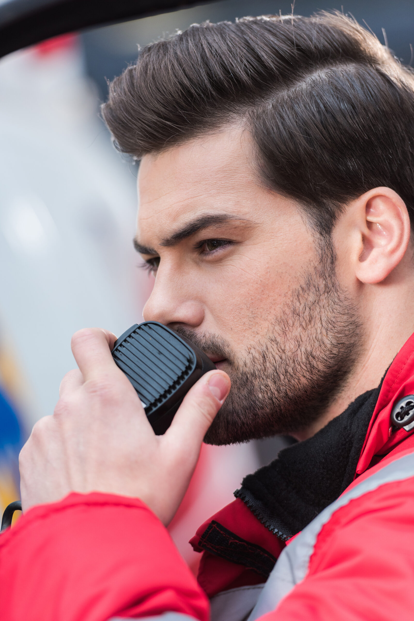 portrait of young handsome male paramedic standing near ambulance and talking by portable radio About Metrotalk